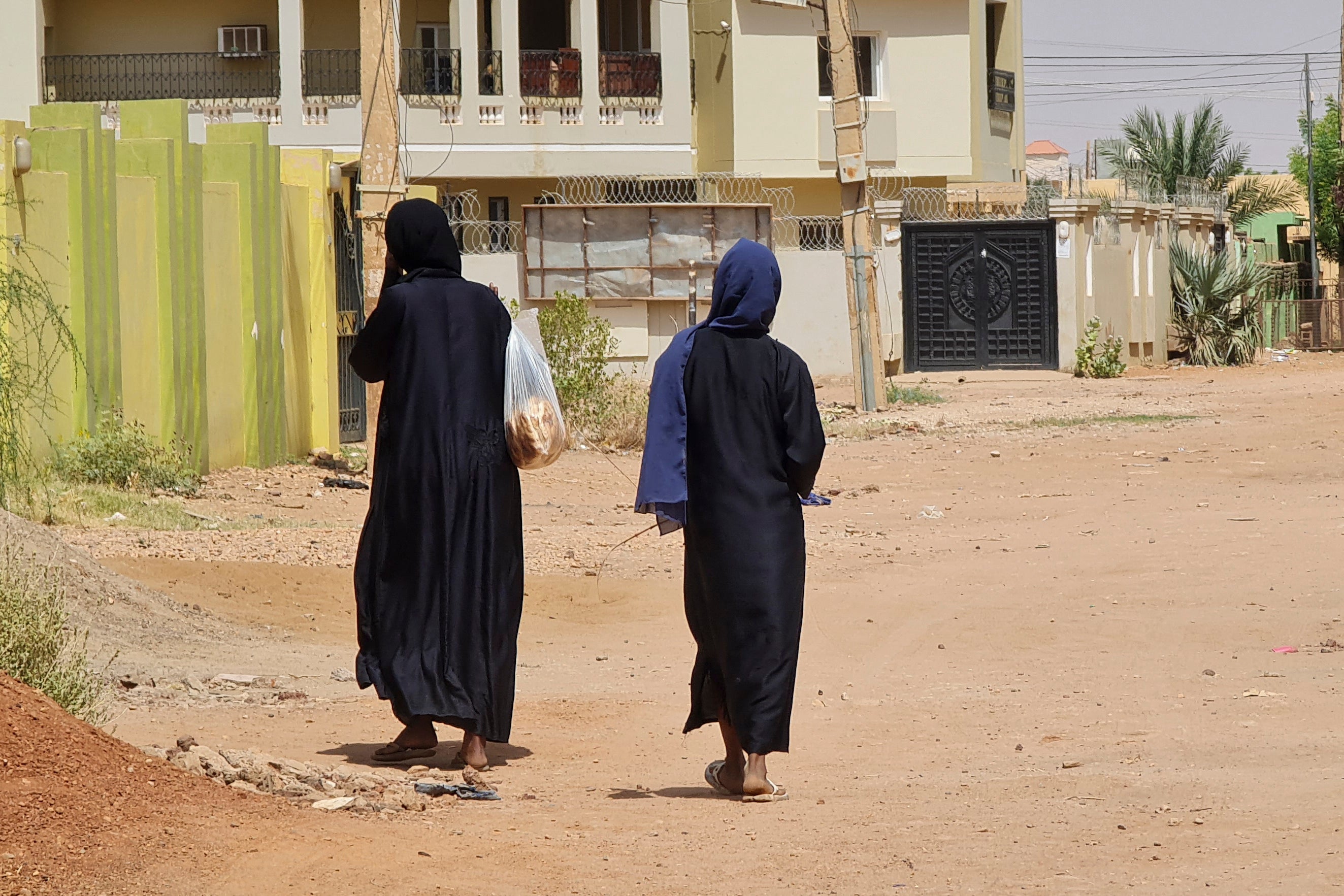 Two unidentifiable women walk down a city street